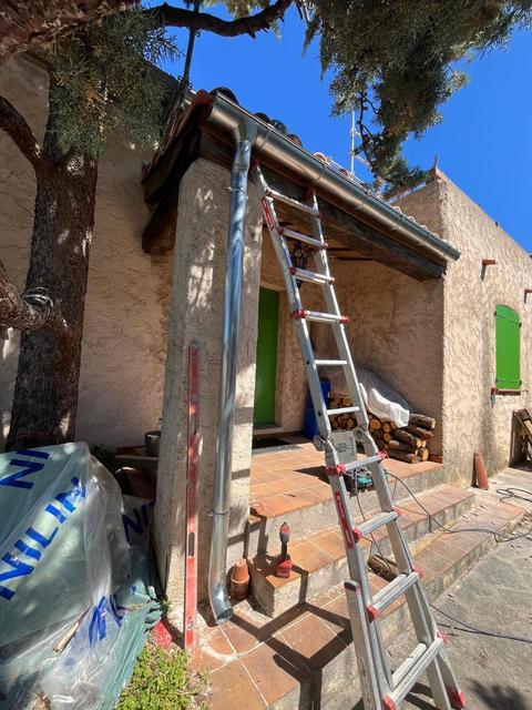 Descente de gouttière en zinc posée à l'angle d'une maison